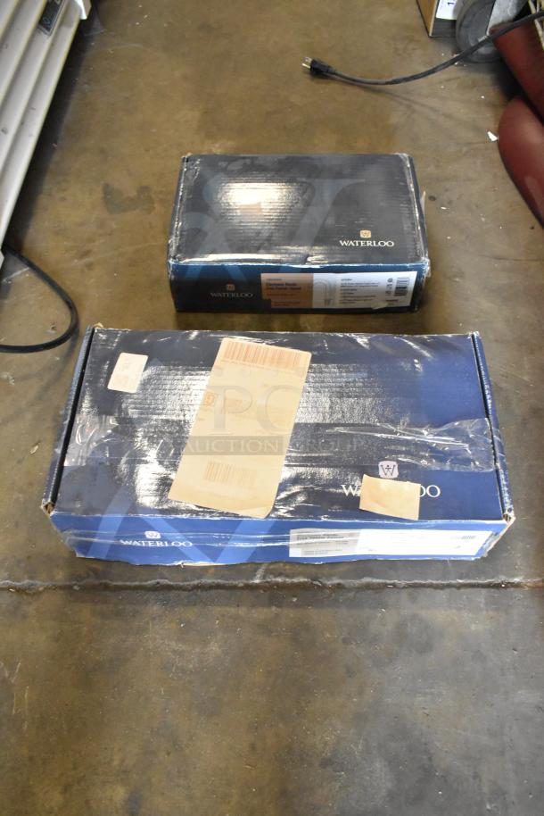 Boxes containing new Waterloo sensor faucets, models 750EFWM448LF and 750EFDMHSBZ, showing logos and labels.