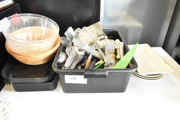 Assorted lot of utensils, trays, bus bin, and bowls. Includes metal and plastic items. Condition varies, some wear visible.