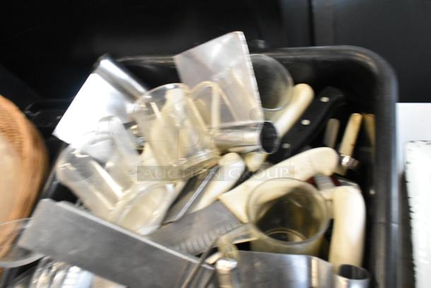 Lot of assorted kitchen items including utensils, trays, and bus bin in mixed condition. Plastic and metal materials visible.