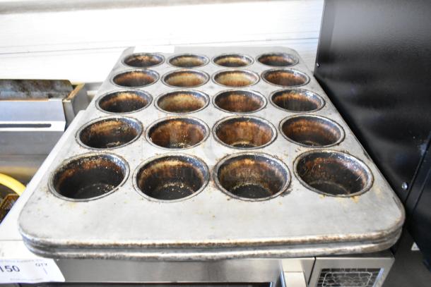 2 metal 20-cup muffin baking pans, showing signs of use, ideal for high-capacity baking needs.
