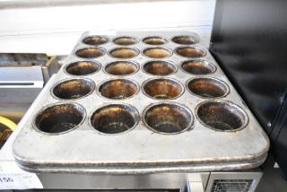 2 metal 20-cup muffin baking pans, showing signs of use, ideal for high-capacity baking needs.