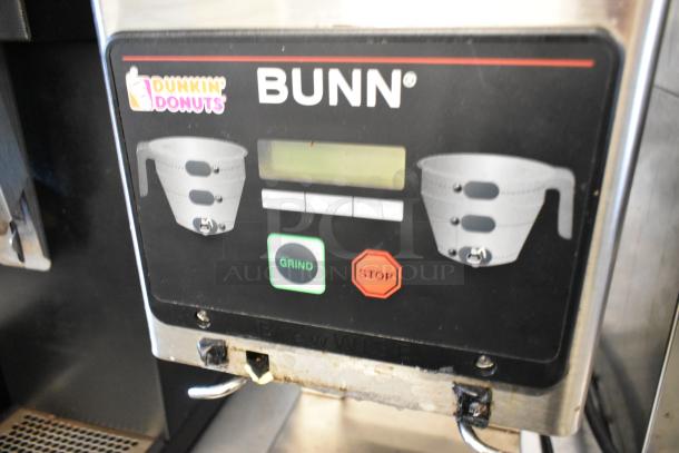 Bunn MHG stainless steel commercial coffee grinder with dual hoppers. Features grind and stop buttons. 120V, 1 Phase. Dunkin' Donuts logo visible.