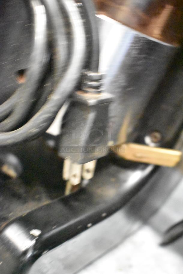 Closer view of electrical cord and plug for a metal commercial espresso bean grinder, showing signs of wear.