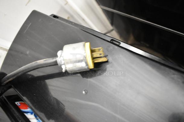 Close-up of McCray metal deli display case power plug, showing a standard three-prong connector attached to a black cord.