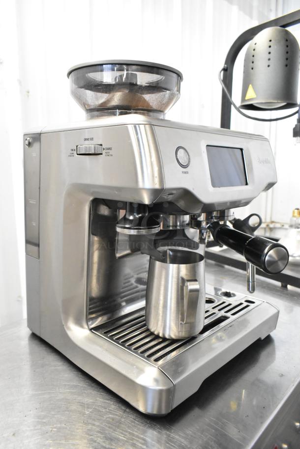 Breville metal countertop espresso machine with bean hopper, portafilter, and stainless steel exterior.