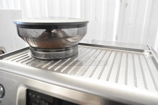 Breville countertop espresso machine with a bean hopper and portafilter. Metal finish, in good condition.