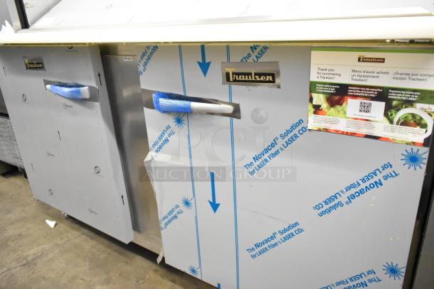 Brand new Traulsen UPT6024-LR stainless steel sandwich prep table with protective wrapping, visible logos, and paperwork.