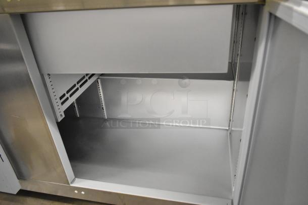 Brand new 2020 Traulsen UPT6024-LR stainless steel sandwich prep table, scratch and dent, on casters, interior view.