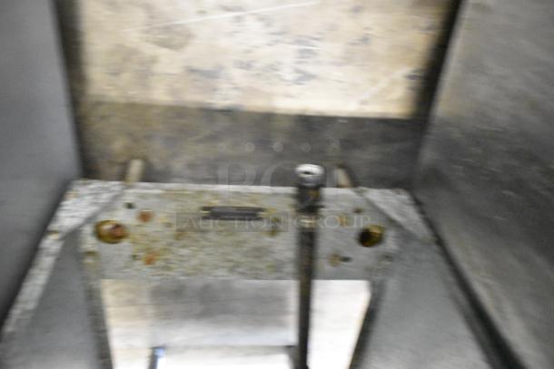 Blurry image of a Qualite QL-9/NG stainless steel commercial deep fat fryer interior, showing some metal parts and wear.