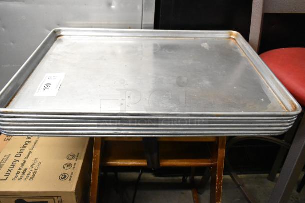 Set of 7 full-size metal baking pans in used condition, stacked. Auction tag indicating lot number 190 attached.