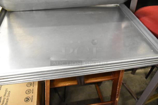 7 metal full-size baking pans stacked. Minor wear visible. Ideal for commercial or home baking.