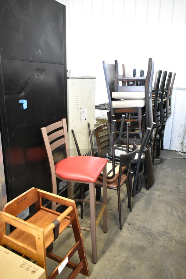 19 assorted chairs including a high chair, bar height chair, and dining chairs in used condition, stacked for auction.