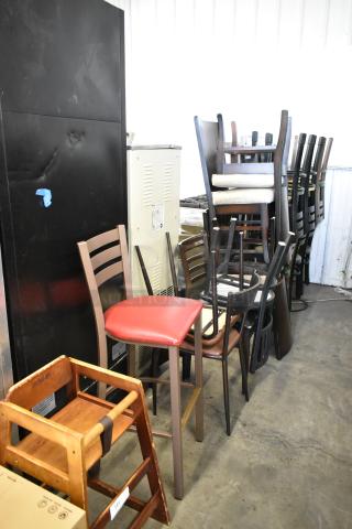 19 assorted chairs including a high chair, bar height chair, and dining chairs in used condition, stacked for auction.