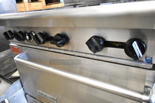 American Range stainless steel gas 6-burner range with oven. Features overshelf, backsplash, and control knobs. Commercial-grade.