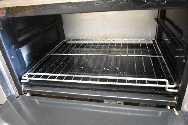 American Range oven interior with clean wire rack, showing minimal wear and scattered crumbs. Commercial-grade appliance.