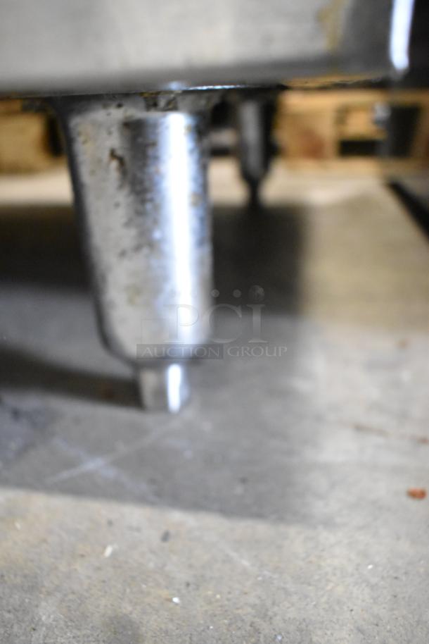 Close-up of a metal leg from an American Range stainless steel commercial gas range, showing signs of wear.