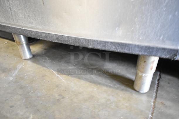 Stainless steel commercial ice bin with sturdy cylindrical legs, used condition with visible wear. Ideal for restaurant use.