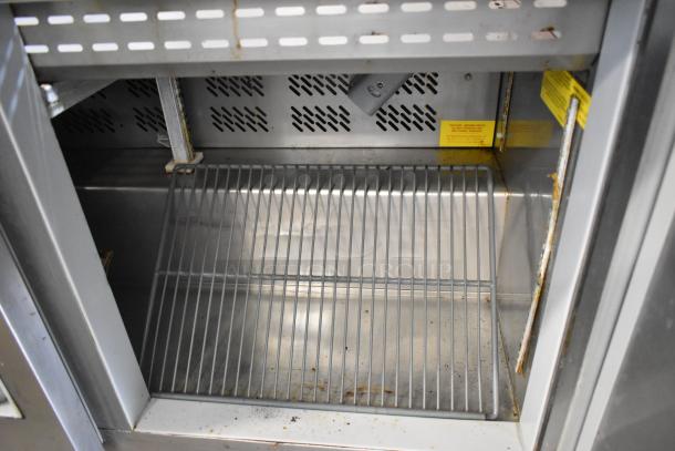 Berg EDMT7230BERG stainless steel prep table interior, showing shelf and perforated ventilation. Some visible wear.