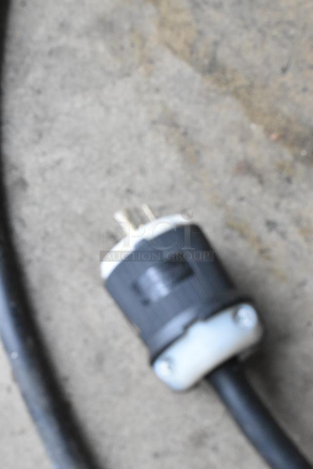 Close-up of a power plug for the Taylor C723-33 soft serve machine, showing a heavy-duty connector on a concrete surface.