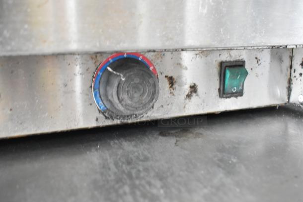 Close-up of a control panel on a stainless steel appliance, showing a dial and switch with visible wear and residue.