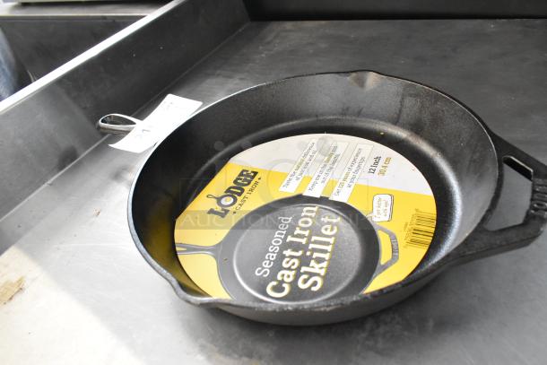 Brand new Lodge Cast Iron Skillet, 12-inch, with visible scratch and dent. Features include seasoning label and sturdy handles.