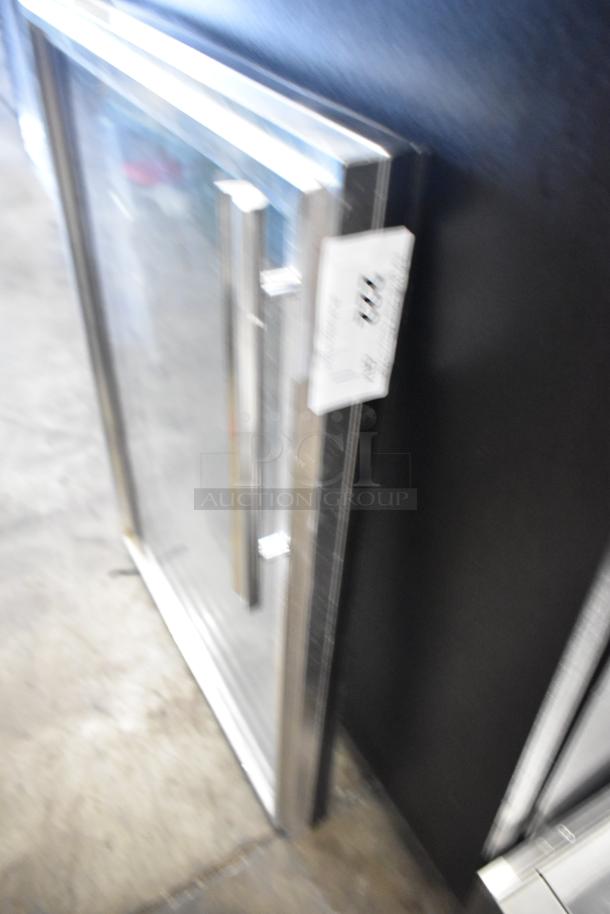 Glass door with metal frame and handle, clear glass, visible auction tag, good condition.
