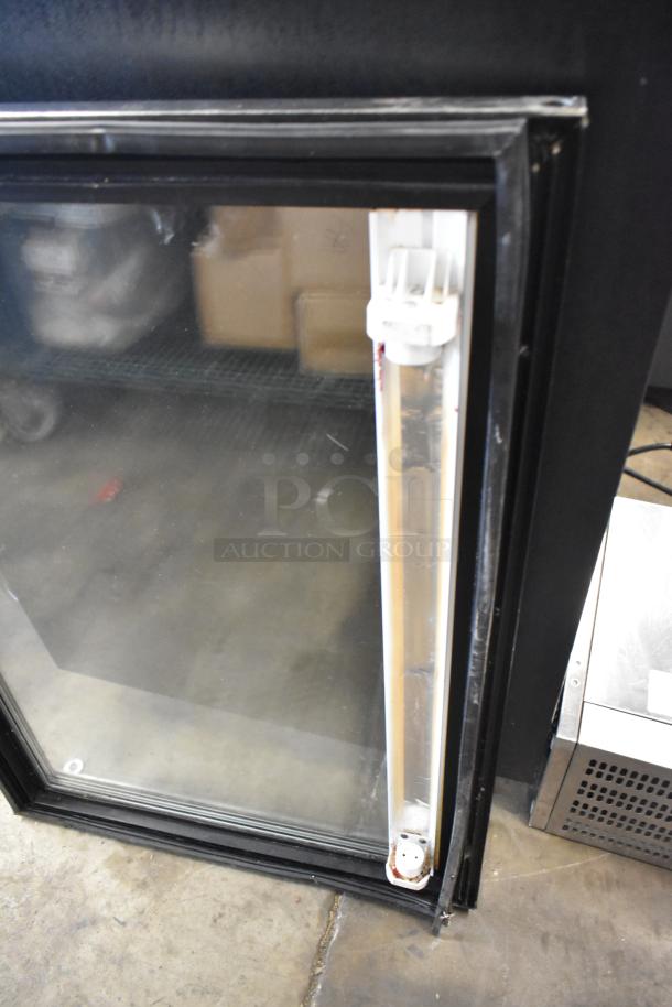 Glass door with black frame, clear panel, and attached handle. Visible wear on frame, suitable for home or commercial use.