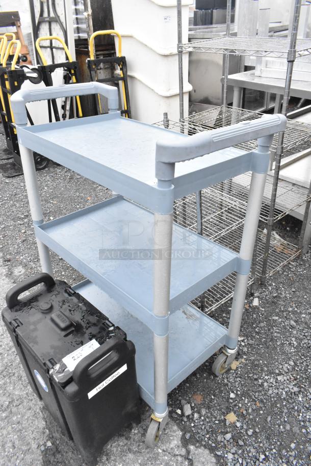 Poly blue and gray 3-tier cart with commercial casters, showing light wear, ideal for storage or transport, sturdy construction.