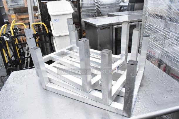 Set of three metal dunnage racks on metal table; sturdy construction, good condition, ideal for storage needs.