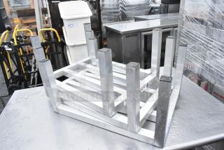 Set of three metal dunnage racks on metal table; sturdy construction, good condition, ideal for storage needs.