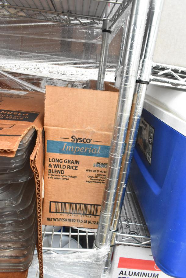 Chrome 4-tier wire shelving unit with Sysco Imperial rice box, metal skillets, poly lids, and beverage holders. Buyer dismantles.