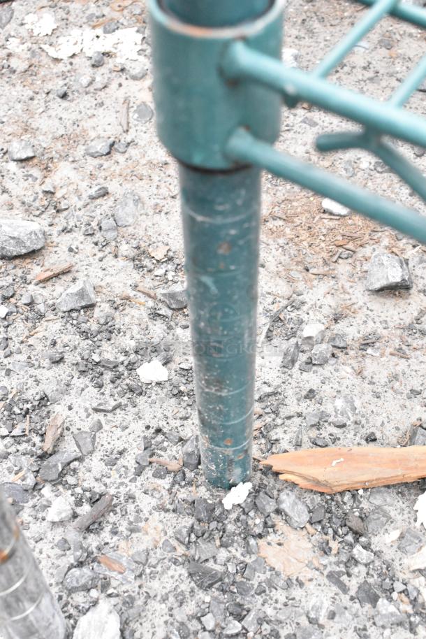 Green finish 2-tier wire shelving leg in outdoor setting, slightly worn. Buyer must dismantle; freight charges apply.