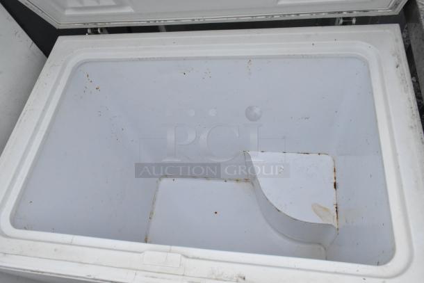 Open white chest freezer interior with signs of use. This item is part of a set including a Frigidaire Reach In Freezer. 115 volts.