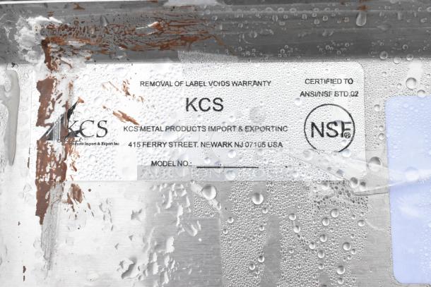 Stainless steel 3 bay sink with left side drain board and faucet. Label shows KCS Metal Products, NSF certified.
