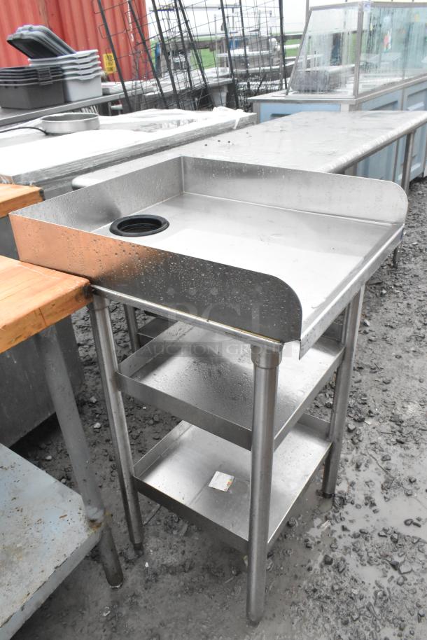 Stainless steel table with two under shelves, features a raised lip and drain hole. Slight wear visible.