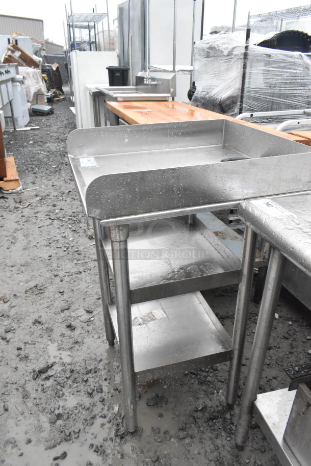 Stainless steel table with two under shelves, showing minor wear, ideal for kitchen use. Sturdy construction, easy to clean.