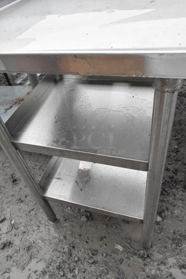 Stainless steel table with two under shelves, showing signs of outdoor exposure, sturdy construction.