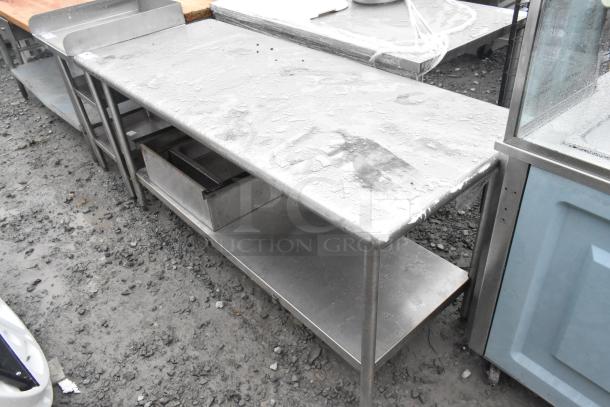 Stainless steel table with under shelf, suitable for kitchen use. Visible wear on surface; sturdy condition.
