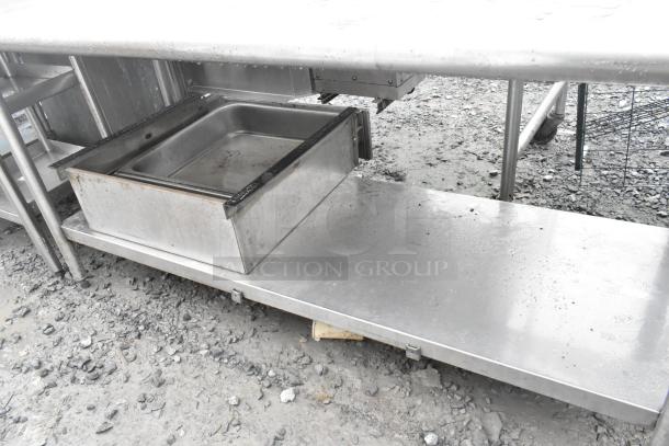 Stainless steel table with under shelf, featuring durable construction. Shows signs of use, ideal for commercial kitchens.