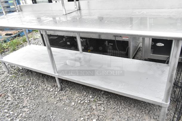 Stainless steel table with under shelf and two-tier over shelf, clean surface, sturdy metal legs, gray color, outdoor setting.