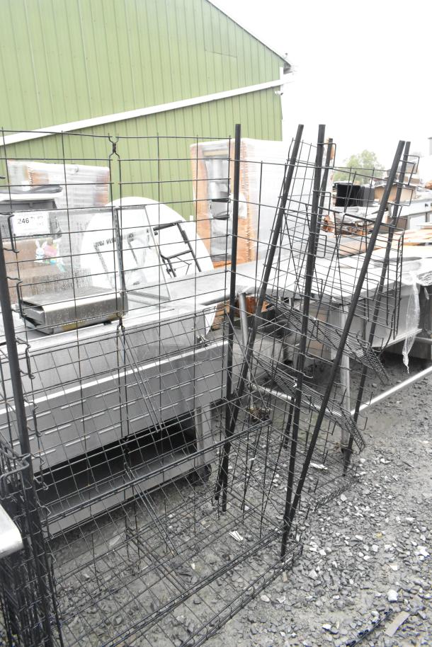 Two black wire shelving units on a gravel surface, showing multiple tiers and sturdy metal construction.