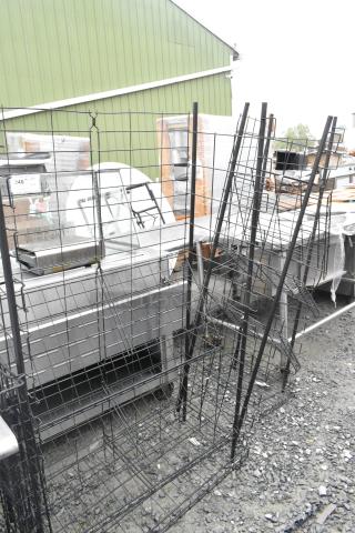 Two black wire shelving units on a gravel surface, showing multiple tiers and sturdy metal construction.
