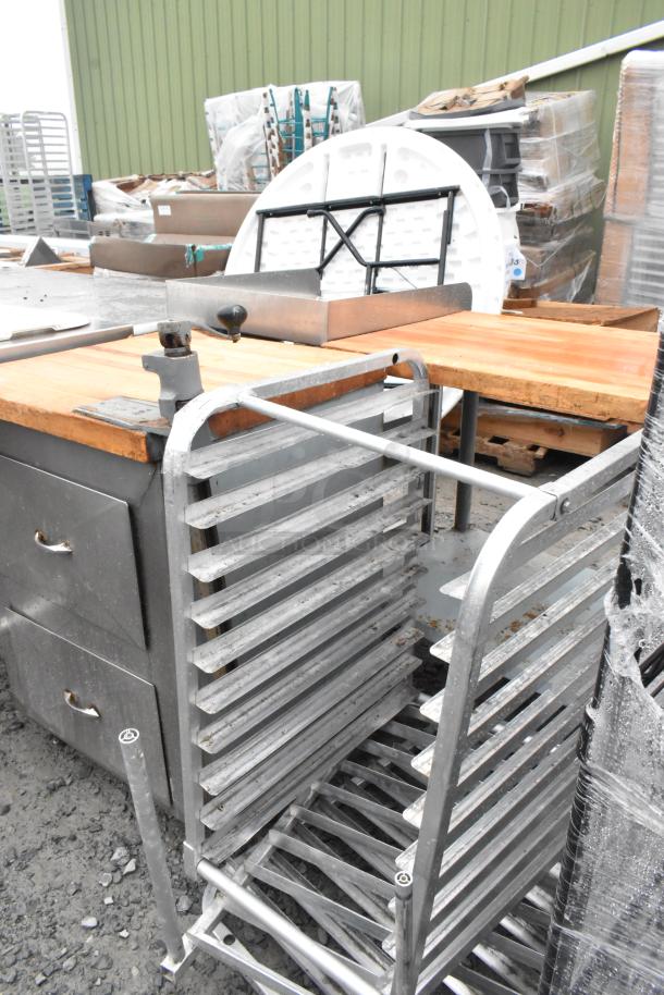 Metal pan rack with multiple horizontal slots, sturdy frame. Used condition with visible wear. Ideal for kitchen storage.