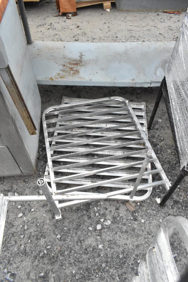 Metal pan rack with diagonal slats, shows signs of wear and rust. Made of sturdy metal, suitable for industrial use.