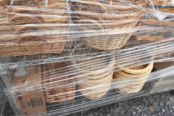 Chrome finish 4-tier wire shelving unit with wicker baskets, wrapped in protective plastic. Buyer must dismantle.