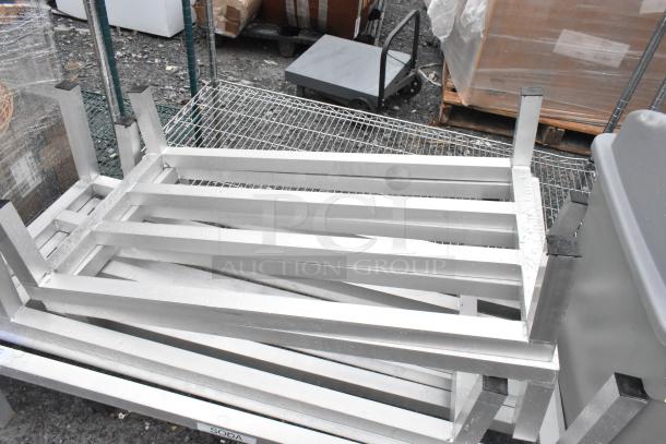 Five metal dunnage racks stacked, in good condition, featuring sturdy horizontal bars. Ideal for storage and organization.