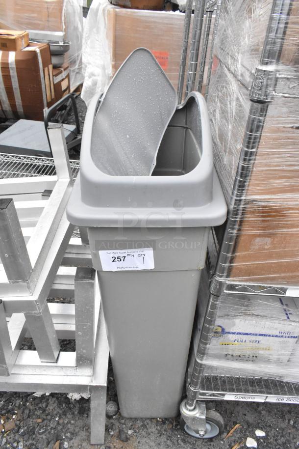 Gray Poly Slim Jim Trash Can, rectangular, used condition, with sticker showing "257 1 QTY," placed outdoors.