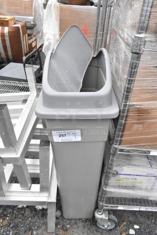 Gray Poly Slim Jim Trash Can, rectangular, used condition, with sticker showing "257 1 QTY," placed outdoors.