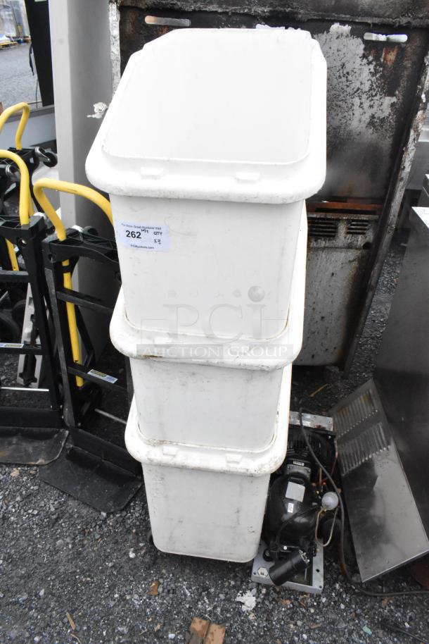 Three white poly ingredient bins on commercial casters, stacked vertically, showing signs of wear, labeled "262 QTY x3".