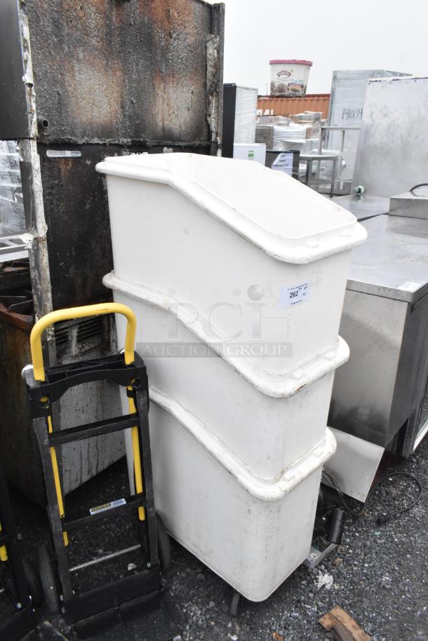 3 white poly ingredient bins on commercial casters, stacked, with visible wear. Auction tag number 262 displayed.
